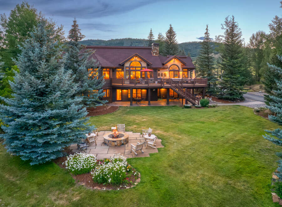 Experience luxury mountain living in this stunning estate, featuring a spacious deck with breathtaking views and a cozy fire pit area perfect for evening gatherings.
