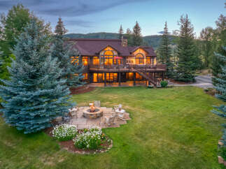 Experience luxury mountain living in this stunning estate, featuring a spacious deck with breathtaking views and a cozy fire pit area perfect for evening gatherings.