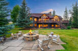 Experience the ultimate mountain retreat with this stunning property, featuring a spacious backyard with a stone fire pit and comfortable log seating, perfect for evening gatherings.