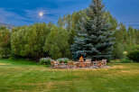 Experience the magic of twilight with this stunning outdoor living space, featuring a stone fire pit surrounded by comfortable Adirondack chairs, perfect for gathering under the moonlight.