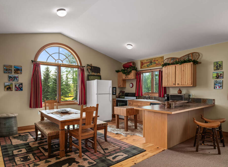 Experience rustic charm in this cozy kitchen, featuring a large arched window with scenic forest views.