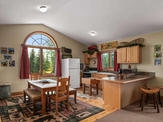 Experience rustic charm in this cozy kitchen, featuring a large arched window with scenic forest views.