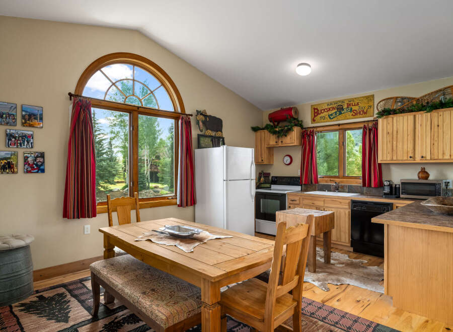 Experience rustic charm in this cozy kitchen featuring a large wooden dining table perfect for family meals.