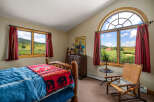 Experience rustic charm in this inviting bedroom, featuring a cozy log bed adorned with a bear-themed blanket.