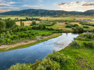 Discover your dream home nestled in a picturesque landscape, offering a serene riverfront setting with lush greenery and rolling hills.