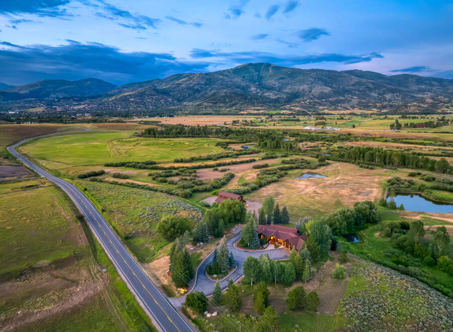 Experience luxury living in this stunning mountain estate, featuring a beautifully lit main residence and a charming guest house.