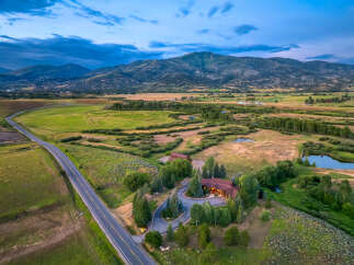 Experience luxury living in this stunning mountain estate, featuring a beautifully lit main residence and a charming guest house.