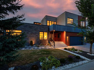 Experience modern luxury in this stunning multi-level home, featuring a striking stone facade and warm wood accents.