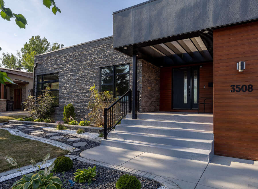 Discover modern luxury with this stunning home featuring a striking stone facade and warm wood accents.