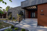 Discover modern luxury with this stunning home featuring a striking stone facade and warm wood accents.