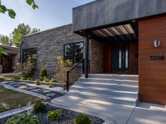 Discover modern luxury with this stunning home featuring a striking stone facade and warm wood accents.