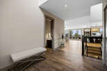 Step into this modern entryway featuring a sleek white bench and rich wood-look tile flooring.