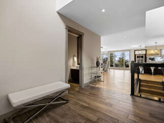 Step into this modern entryway featuring a sleek white bench and rich wood-look tile flooring.