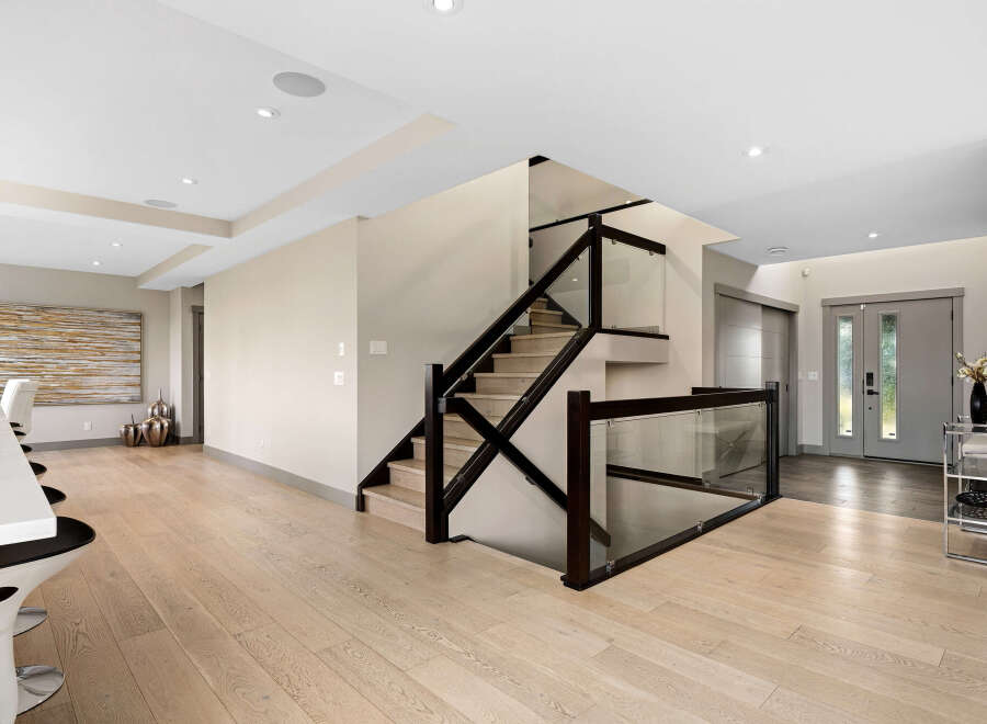 Experience modern luxury in this stunning home featuring a sleek staircase with glass railings and dark wood accents.