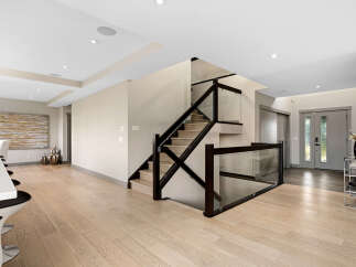 Experience modern luxury in this stunning home featuring a sleek staircase with glass railings and dark wood accents.