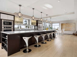 Experience luxury in this modern kitchen featuring a spacious island with sleek bar stools, perfect for entertaining.