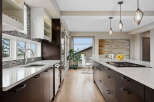 Experience luxury in this modern kitchen featuring sleek dark wood cabinetry and pristine white quartz countertops.