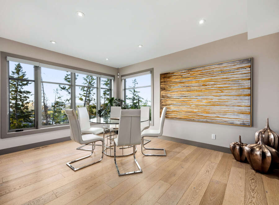 Experience breathtaking views from this elegant dining area, featuring a modern glass-top table surrounded by sleek white chairs.