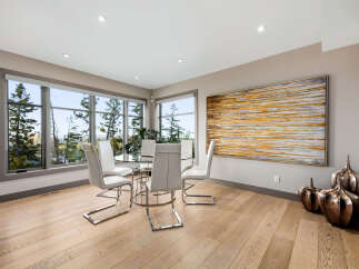 Experience breathtaking views from this elegant dining area, featuring a modern glass-top table surrounded by sleek white chairs.