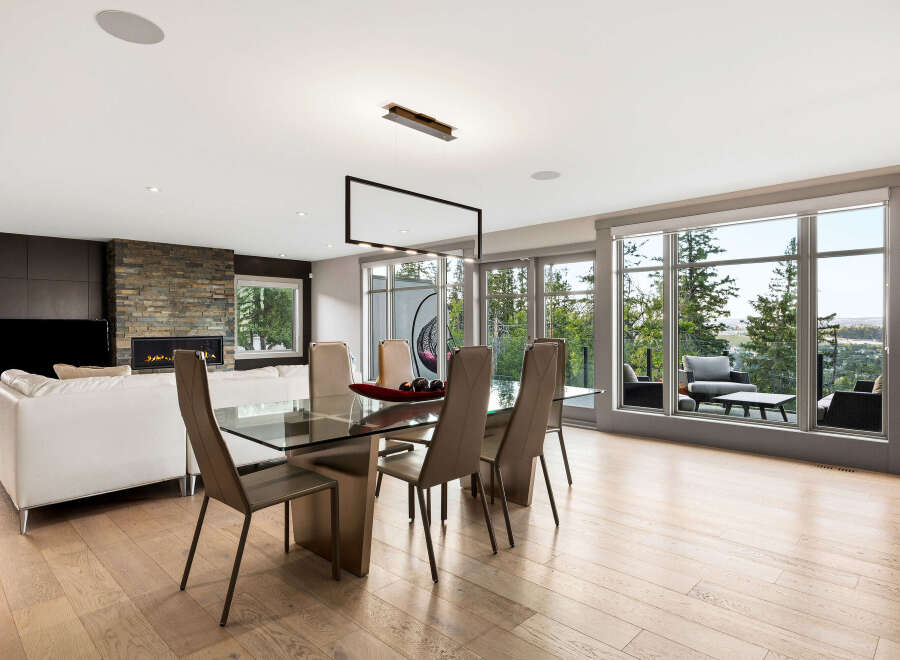 Experience modern luxury in this open-concept living and dining area, featuring a sleek glass dining table and comfortable seating.