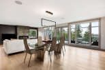 Experience modern luxury in this open-concept living and dining area, featuring a sleek glass dining table and comfortable seating.