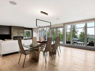 Experience modern luxury in this open-concept living and dining area, featuring a sleek glass dining table and comfortable seating.