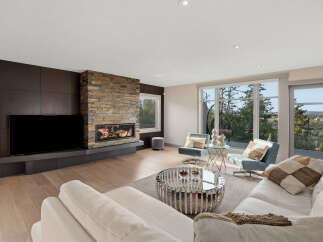 Experience modern luxury in this stunning living room, featuring a sleek entertainment unit and a captivating stacked stone fireplace.