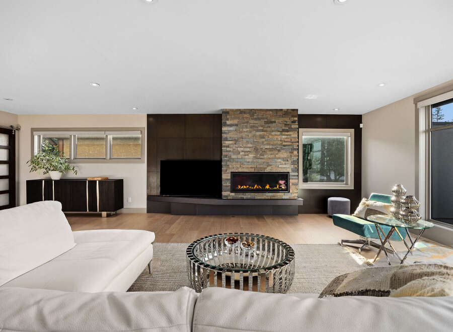 Experience modern luxury in this stunning living room, featuring a sleek white sectional sofa and a captivating stone-clad fireplace.
