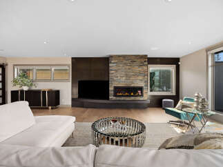 Experience modern luxury in this stunning living room, featuring a sleek white sectional sofa and a captivating stone-clad fireplace.