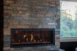 Experience modern luxury with this stunning fireplace, featuring a stacked stone facade and a sleek, linear gas insert.