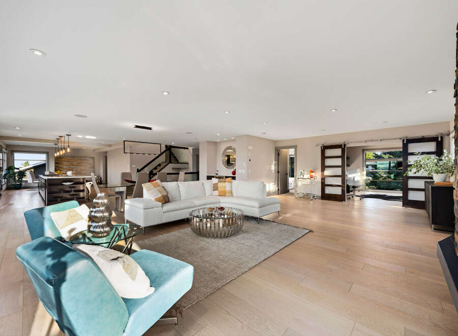 Experience luxurious open-concept living in this stunning modern home, featuring a spacious living area with a sectional sofa and a sleek coffee table.