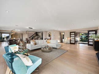 Experience luxurious open-concept living in this stunning modern home, featuring a spacious living area with a sectional sofa and a sleek coffee table.