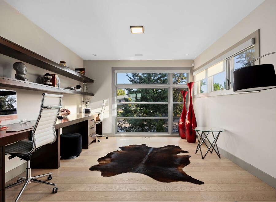 This modern home office features a sleek, built-in desk with ample workspace and comfortable ergonomic chairs.