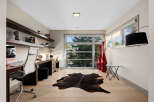 This modern home office features a sleek, built-in desk with ample workspace and comfortable ergonomic chairs.