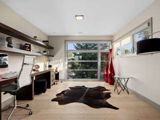 This modern home office features a sleek, built-in desk with ample workspace and comfortable ergonomic chairs.