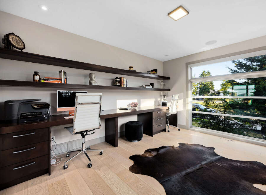 This modern home office features a sleek, dark wood desk with ample workspace, complemented by a comfortable white executive chair.