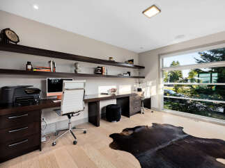 This modern home office features a sleek, dark wood desk with ample workspace, complemented by a comfortable white executive chair.