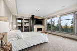 Experience luxury living in this master bedroom, featuring a cozy fireplace and a large TV for ultimate relaxation.