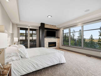 Experience luxury living in this master bedroom, featuring a cozy fireplace and a large TV for ultimate relaxation.