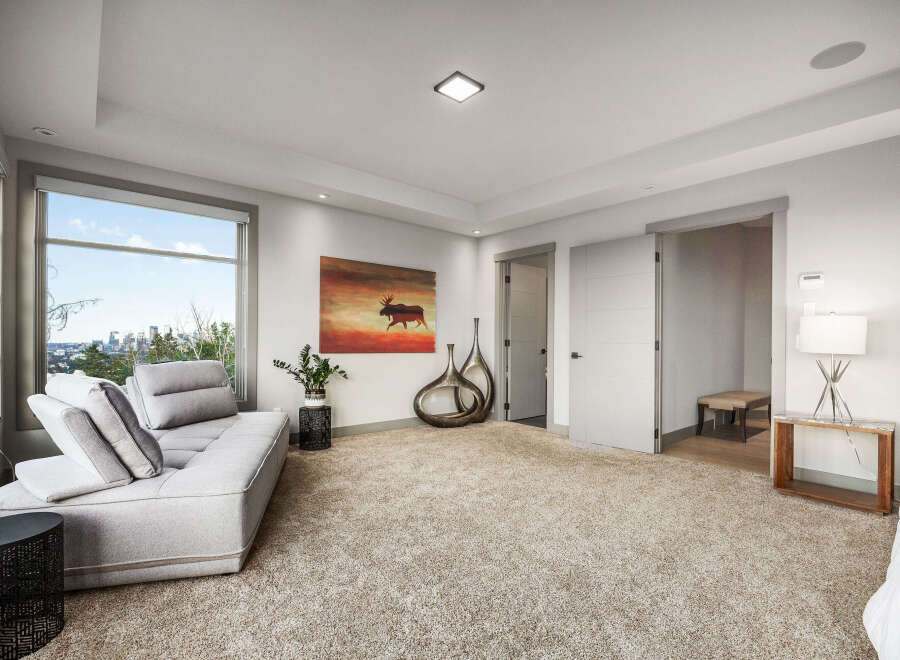 Experience luxury living in this spacious bedroom featuring a plush sectional sofa and a large window with breathtaking city views.