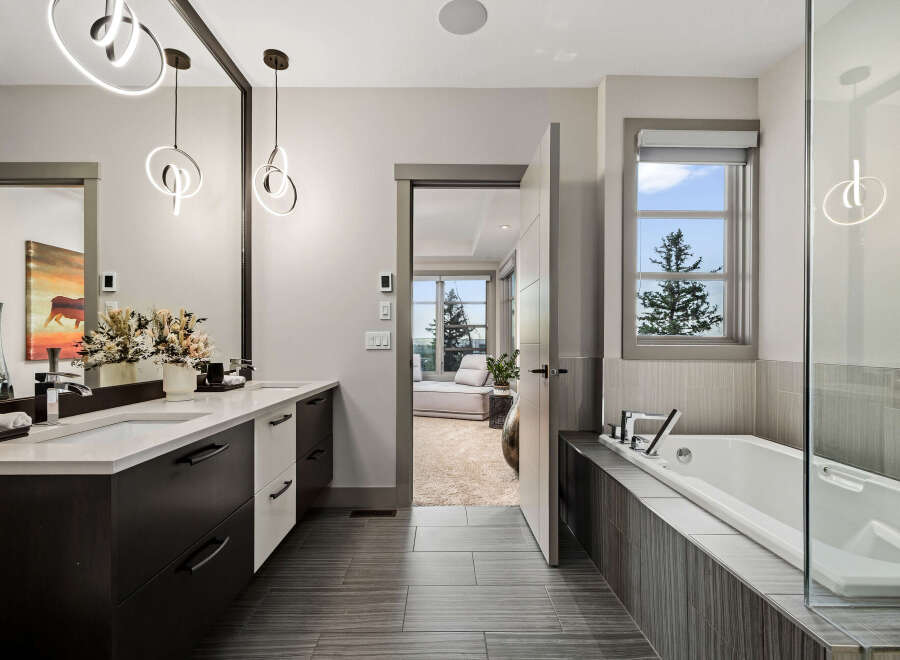 Experience luxury in this stunning bathroom featuring a sleek double vanity with modern pendant lighting and a spacious soaking tub.
