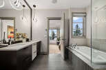 Experience luxury in this stunning bathroom featuring a sleek double vanity with modern pendant lighting and a spacious soaking tub.