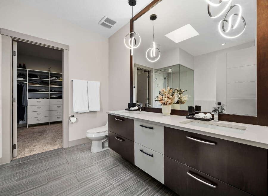 This modern bathroom features a spacious walk-in closet with ample shelving and drawers, perfect for organization.