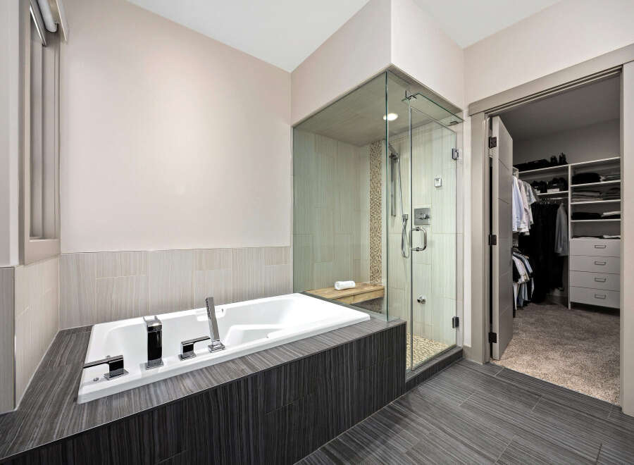 Experience luxury in this modern bathroom featuring a deep soaking tub and a spacious glass-enclosed shower with a built-in bench.