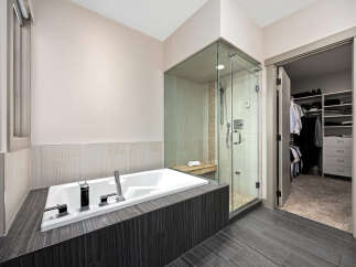 Experience luxury in this modern bathroom featuring a deep soaking tub and a spacious glass-enclosed shower with a built-in bench.