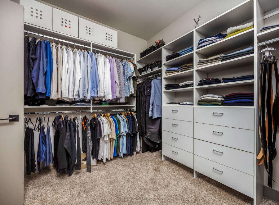 Discover organized luxury in this spacious walk-in closet, featuring ample hanging space for shirts and jackets, complemented by neatly stacked shelves for folded clothing.