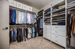 Discover organized luxury in this spacious walk-in closet, featuring ample hanging space for shirts and jackets, complemented by neatly stacked shelves for folded clothing.
