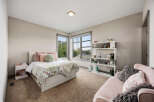 This charming bedroom features a cozy queen-size bed with a floral comforter and plush pillows, complemented by a white nightstand and a fluffy throw blanket.