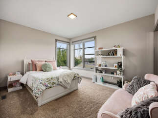 This charming bedroom features a cozy queen-size bed with a floral comforter and plush pillows, complemented by a white nightstand and a fluffy throw blanket.