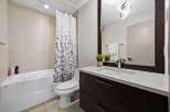This modern bathroom features a sleek white bathtub with a decorative shower curtain, complemented by a clean-lined toilet.